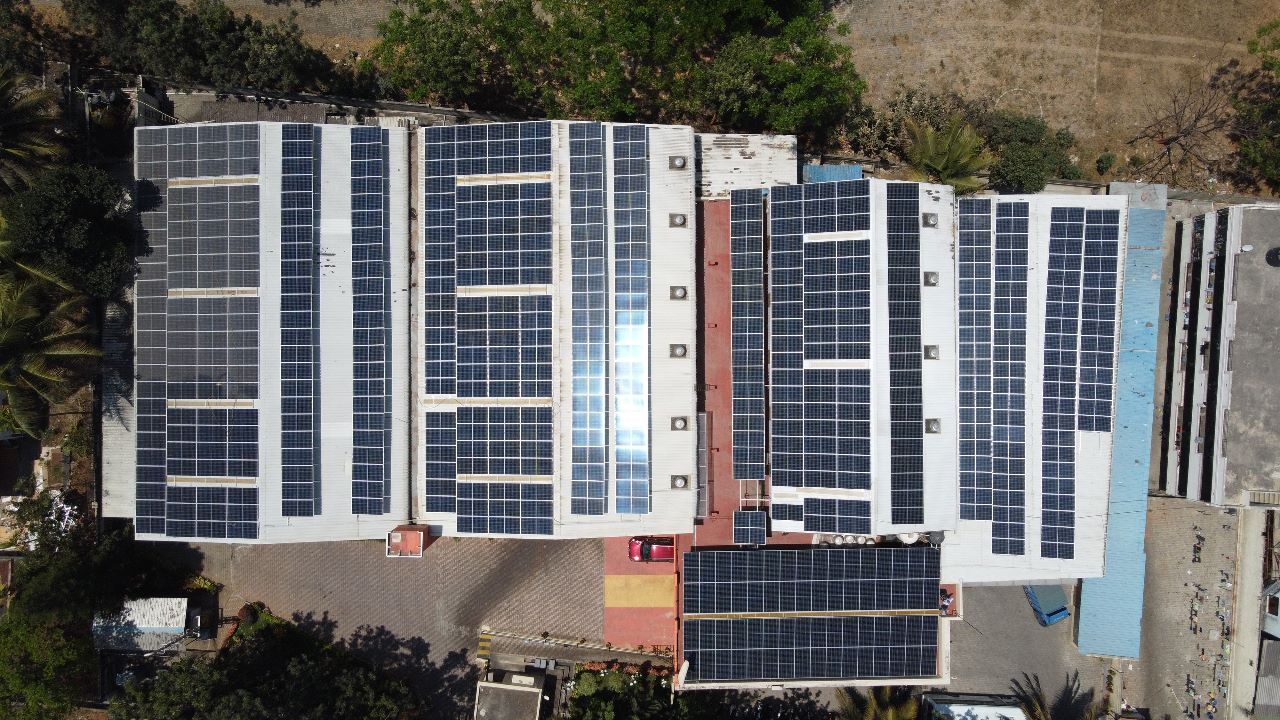 Aerial view of a large Powergate rooftop solar installation across several factory roofs